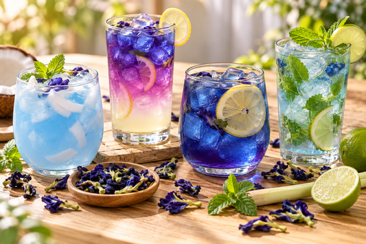 Four butterfly pea flower mocktails with dried blue flowers, mint and lime
